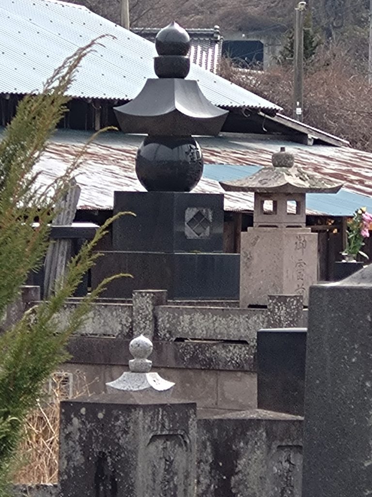 武田菱の入った黒い墓碑と石灯籠が見える、武田信繁の墓所の近景。